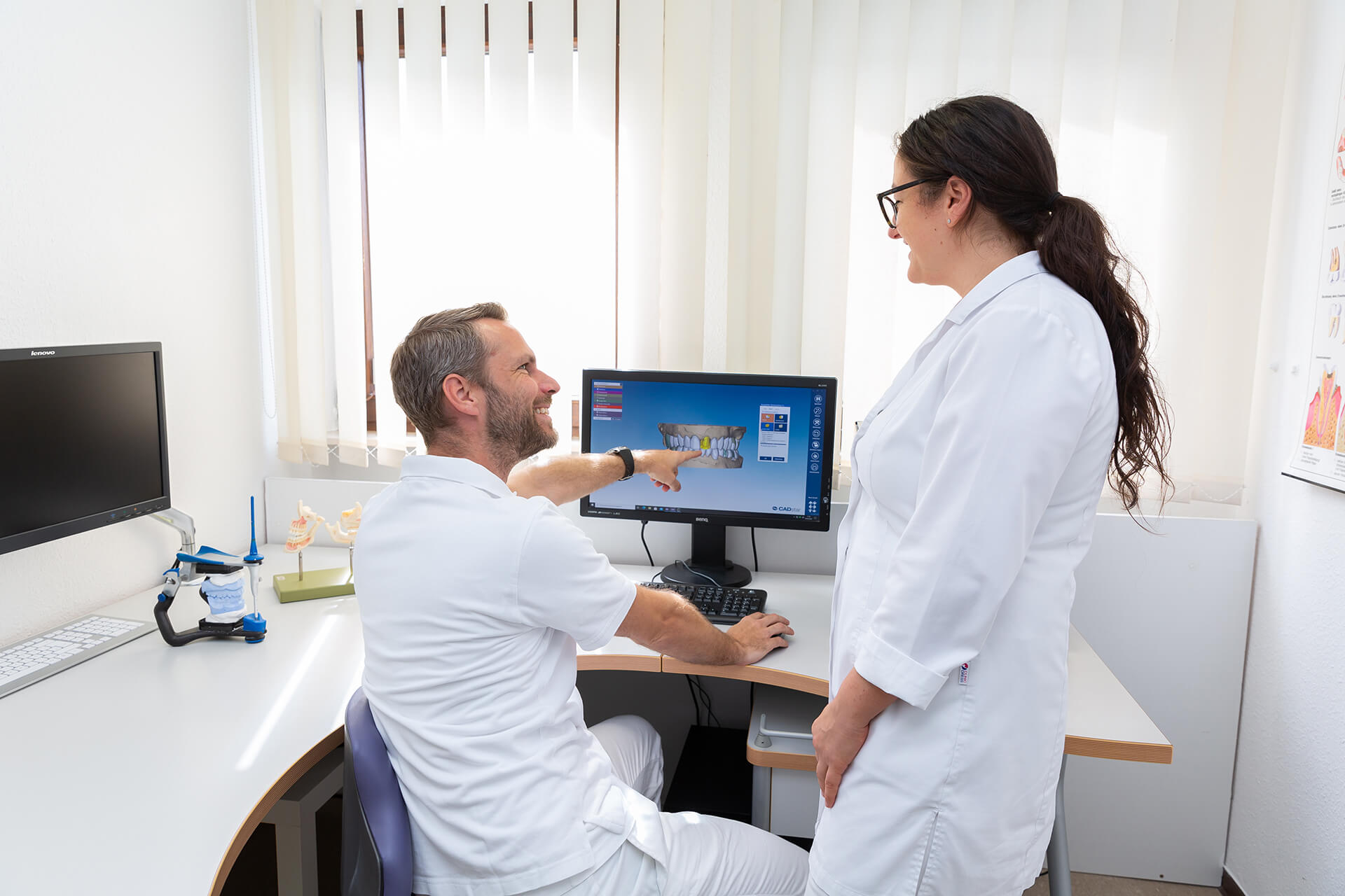 Besprechung am Computer mit einem Gebiss auf dem Monitor