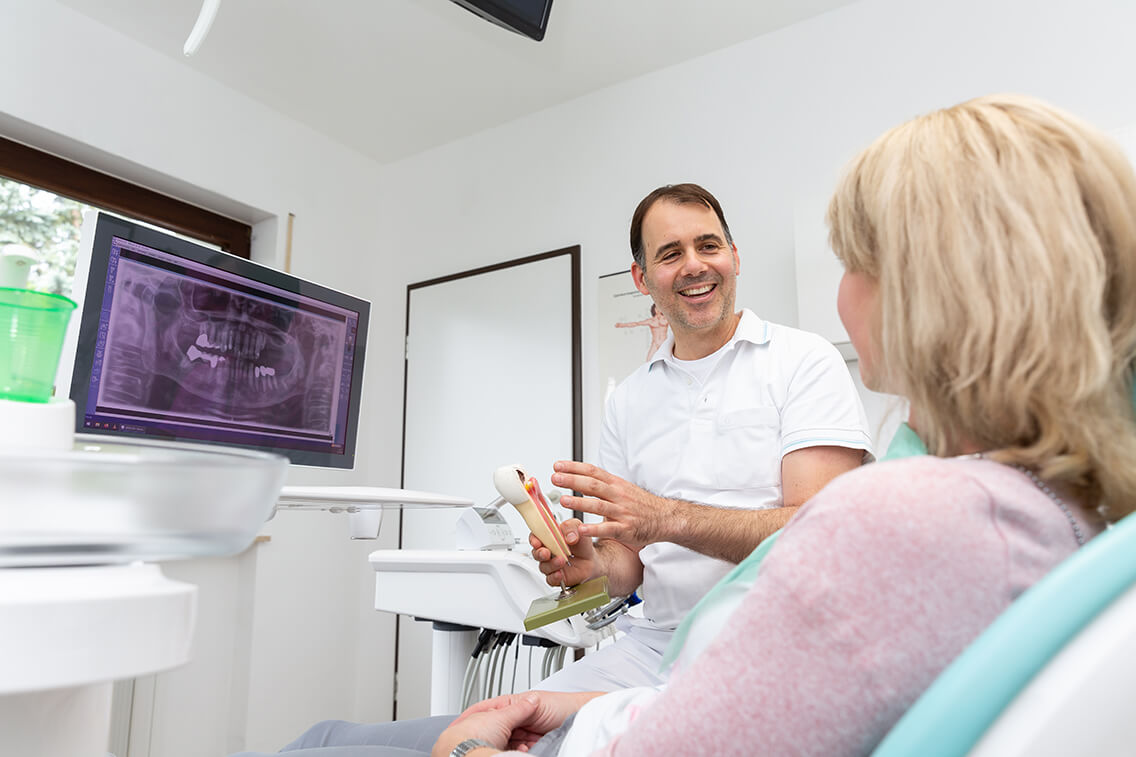 Herr Dr. Reimer erklärt einer Patientin den Aufbau der Zähne mit Blick auf den Monitor