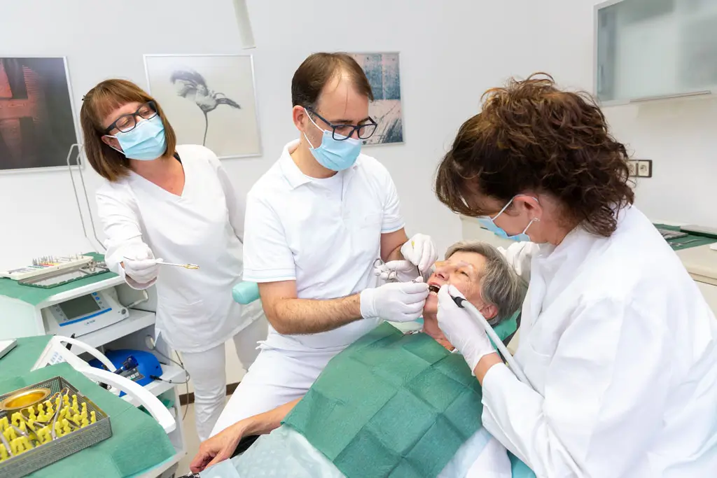 Implantat-Behandlung Hände halten Zahnmodell mit Pinzette und bemalen es mit feinem Pinsel über Farbpalette mit verschiedenen Farbtönen