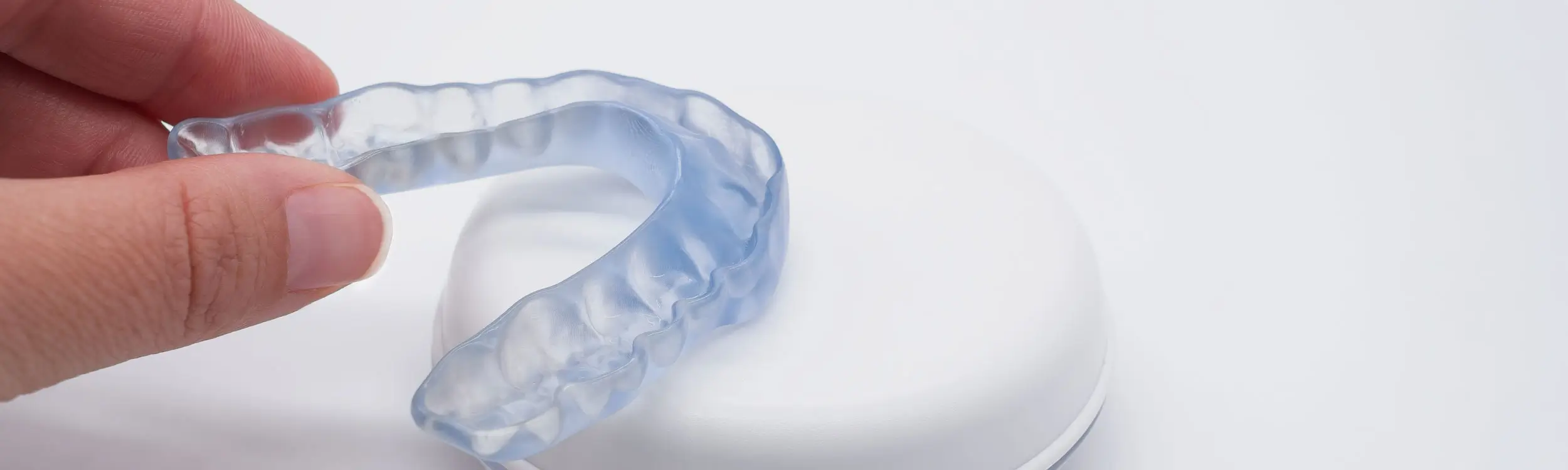 Zahnschiene Hand hält transparente Zahnschiene über weißem runden Behälter